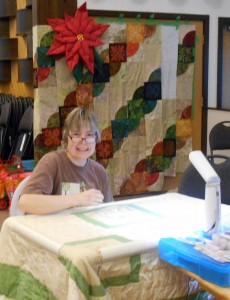 Note the wonderful quilted Pointsettia over Tricia's shoulder.  That's Annie's project on the wall behind